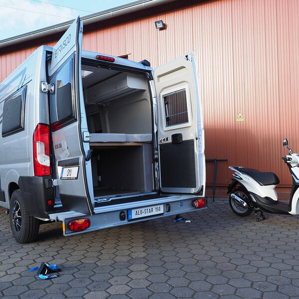 SMV Alu-Star 150 KW montiert an Kastenwagen. Geöffnete Hecktüren und daneben steht ein Roller. 